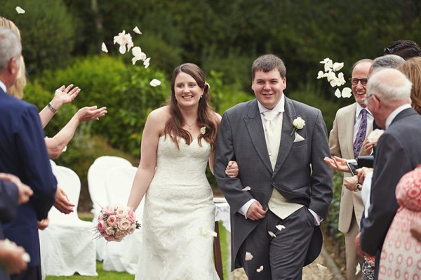 People throwing flowers petals at the bride and groom