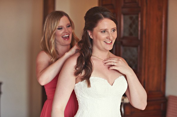 A bridesmaid putting a necklace on the bride