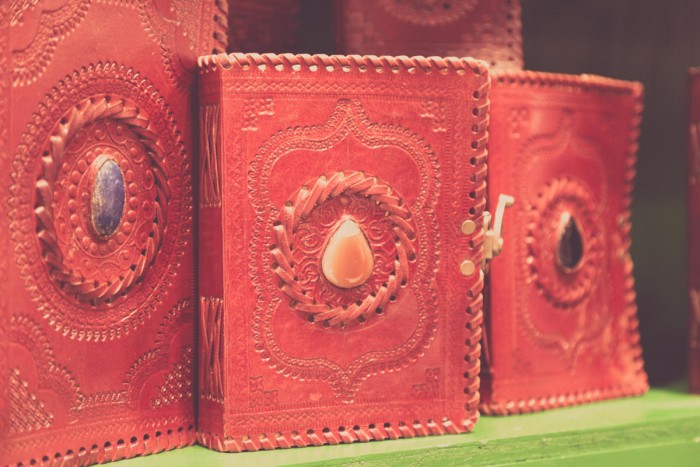 Three red leather journals with gems in the centre