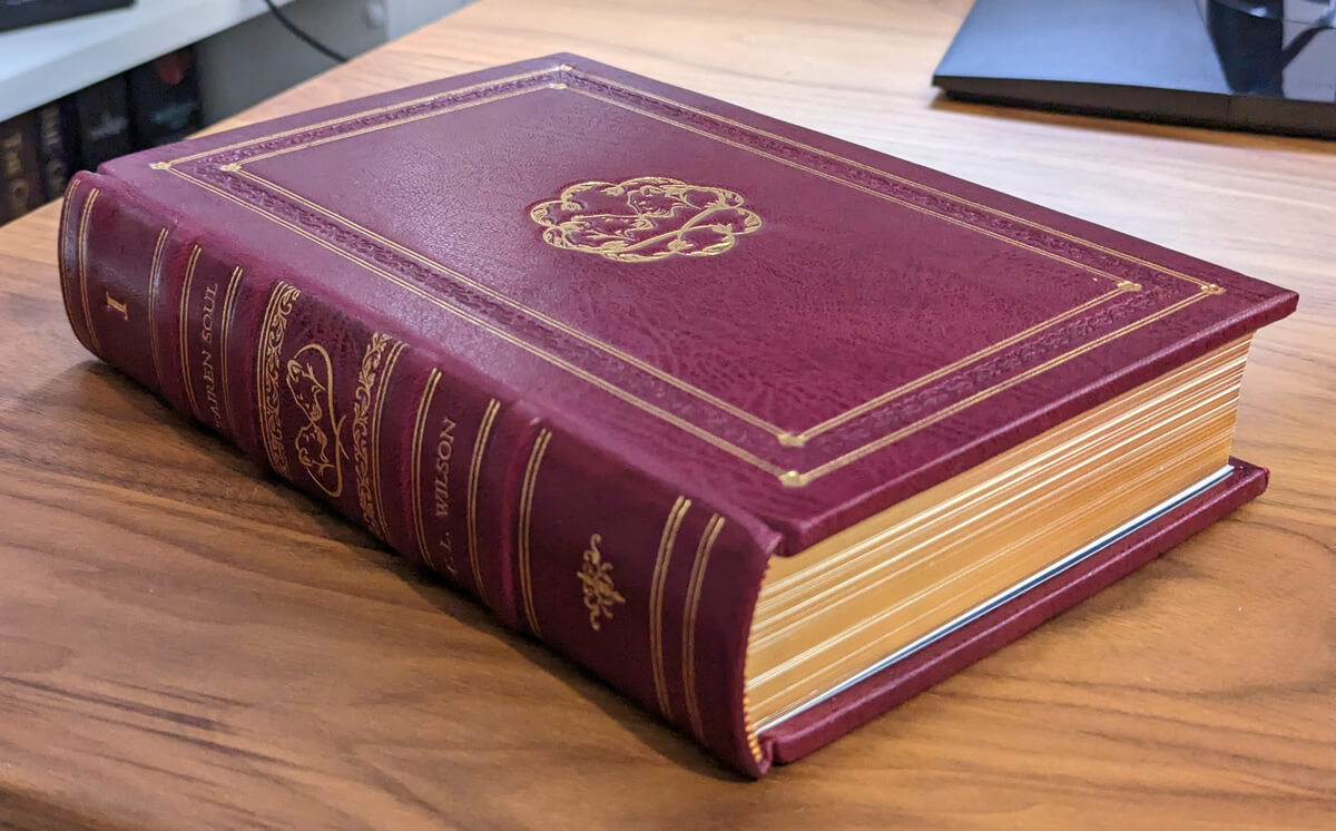 Photo of a leather-bound edition of Tairen Soul. It's in a red/maroon colour leather with gold foil and gilded edges.