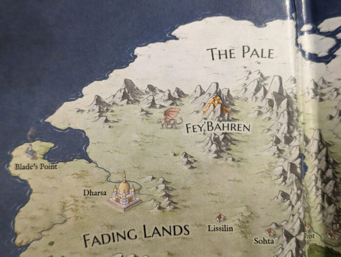 Close up photo of the map, showing the "Fading Lands" region. There's a volcano in a mountainous region, and next to it is a tairen. (Large cat with wings.)